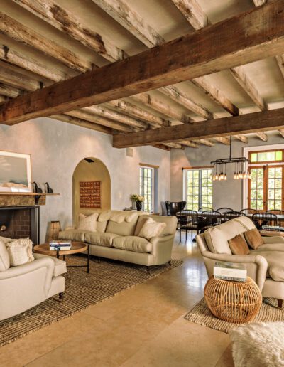 Spacious living room with rustic wooden beams, a stone fireplace, and earth-toned furnishings.