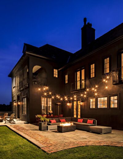 Luxury house with outdoor patio and fire pit illuminated at dusk.